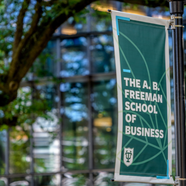 exterior photo of the Goldring/Woldenberg Business Complex front entrance showing a light pole with a Freeman School of Business banner on it