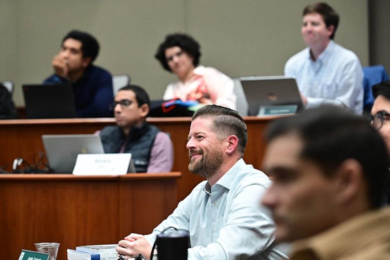 Man smiling in a classroom setting, looking to the left.