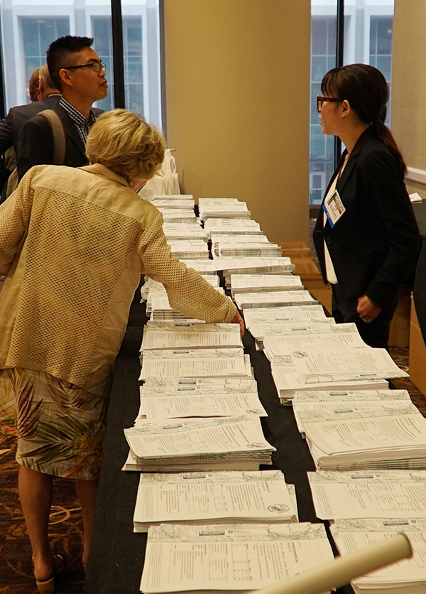 People receive copies of the printed reports at a table while registering for a past conference..