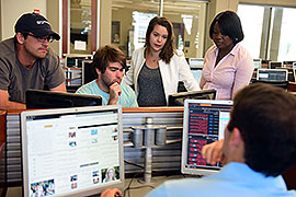 Students working around computers in the mock trading room.
