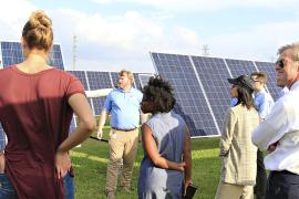 Students outside surrounded by solar panels discussing energy efficiencies.