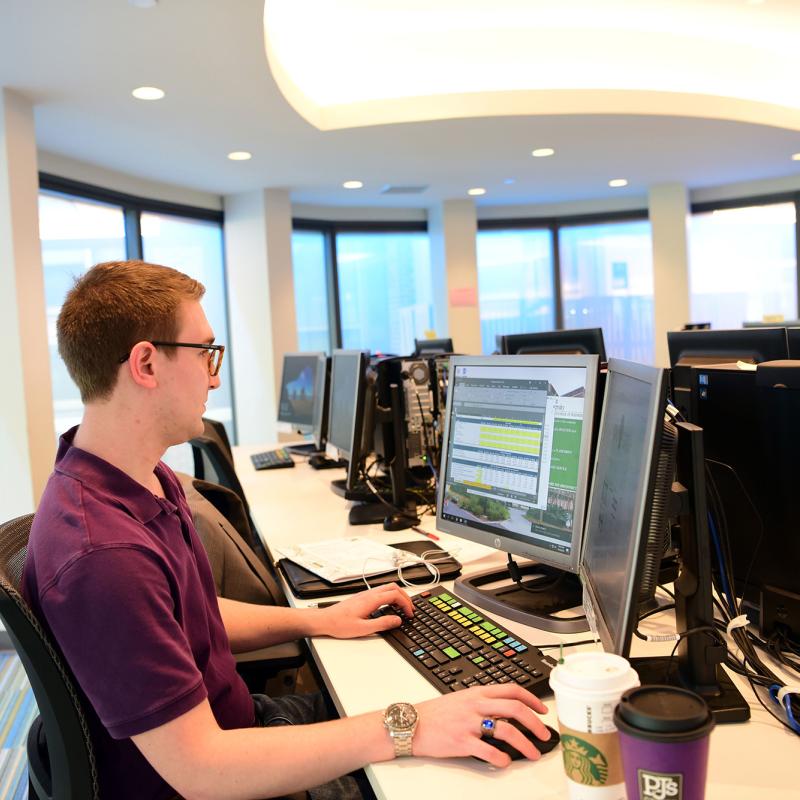 Male student working at desk with monitors.