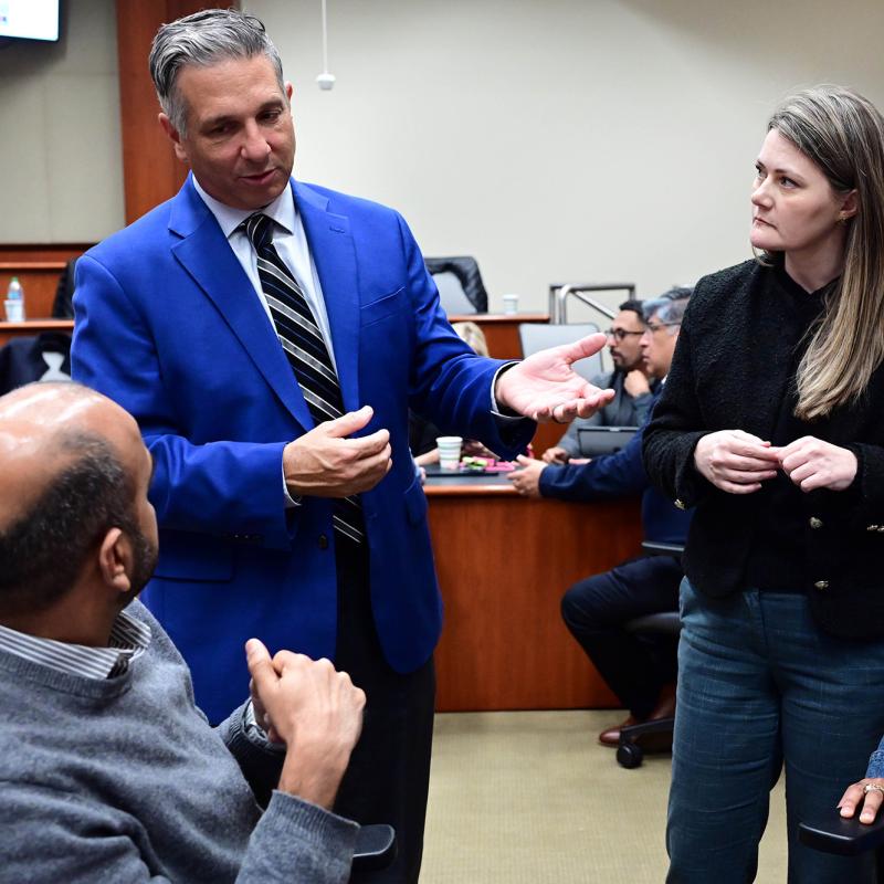 Freeman faculty member having a discussion with a group of Executive MBA students during class instruction.