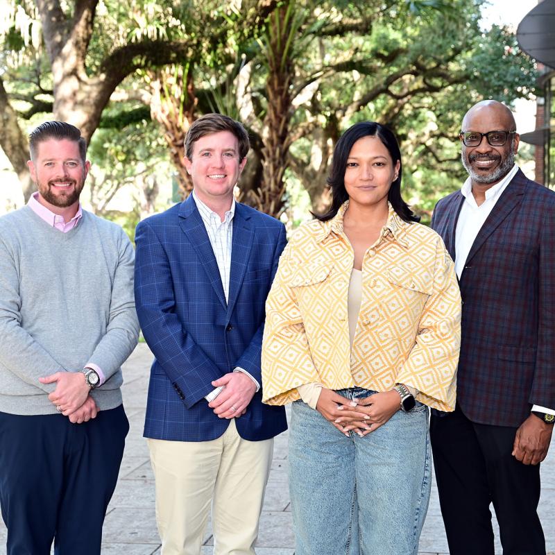 A group photo of Executive MBA students standing in front of the Goldring/Woldenberg Business Complex.