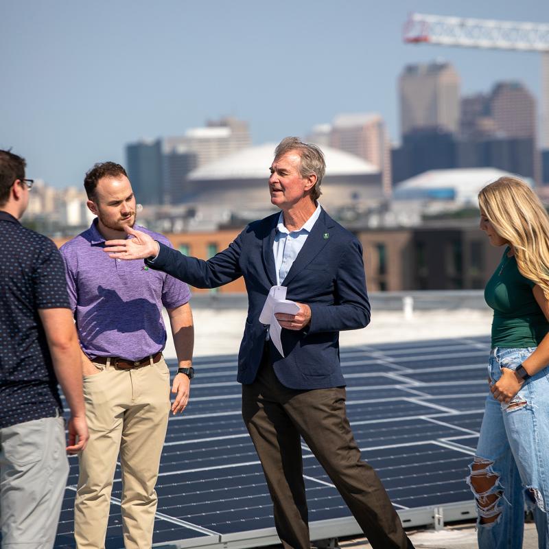Freeman faculty member and executive directory of the Tulane Energy Institute speaking to students on a roof top with solar panels.