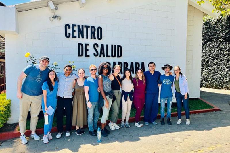 Tulane MBA/MD students and others in casual clothes and scrubs standing outside Centro de Salud Barbará.