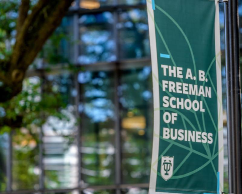 exterior photo of the Goldring/Woldenberg Business Complex front entrance showing a light pole with a Freeman School of Business banner on it