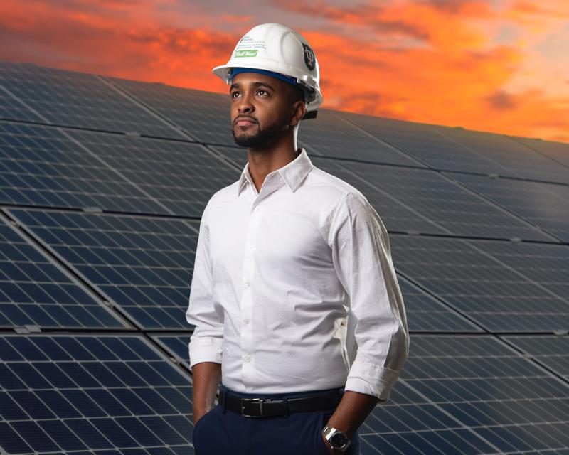 Freeman student Mohamed standing in front of a solar panel array.