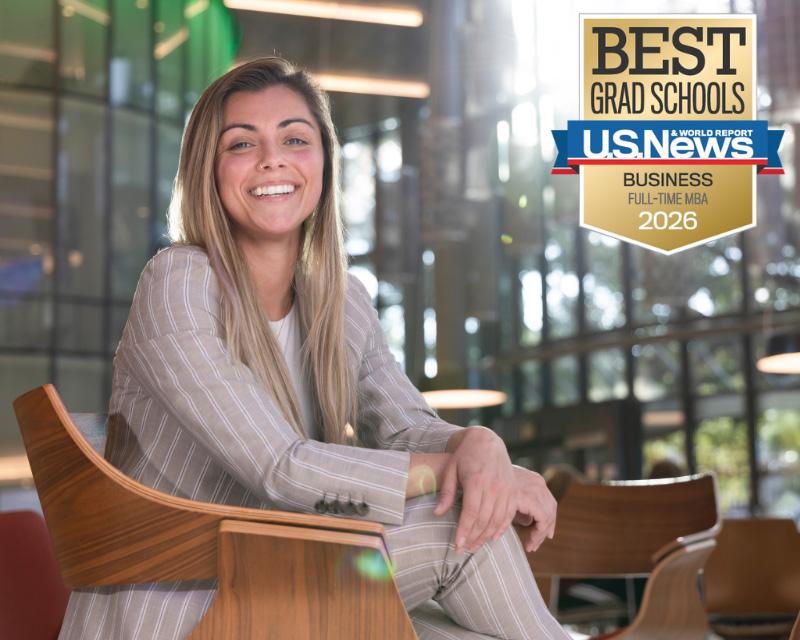 Woman in pinstripe suit smiles, seated, with U.S. News &amp; World Reports 2026 Best Full-Time MBA logo.